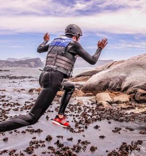 a man in a wetsuit jumping on some rocks