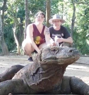 一名男子和一名女子坐在一只大鳄鱼旁边