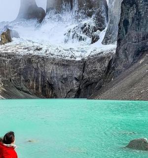a woman standing in the water in front of a mountain