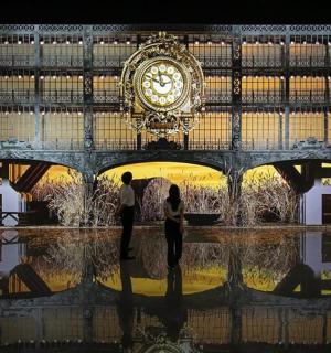 two people are standing in front of a large clock