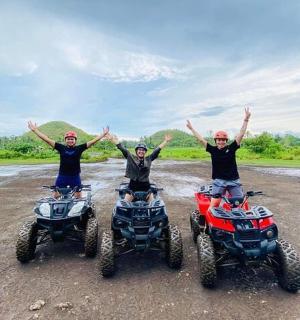 kolm inimest ATV-dega kruusateel, käed üleval