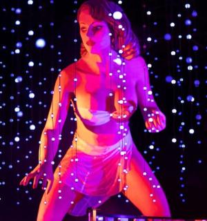 a woman is standing on a stage with purple lights