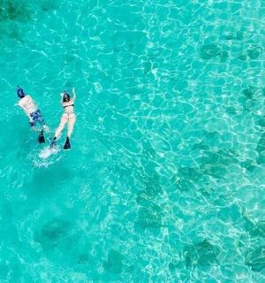a person standing in the water with a snorkeler