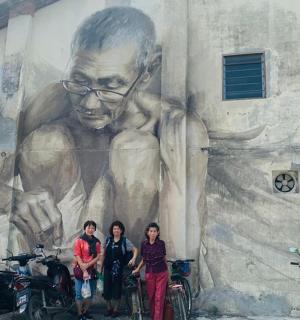 a group of people standing in front of a mural of a man