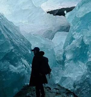 osoba stojící před ledovou jeskyní