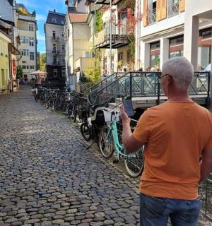 Ένας άντρας που στέκεται σε έναν δρόμο κοιτάζοντας το κινητό του