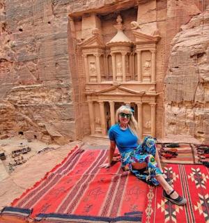 a woman sitting on a rug in front of a building