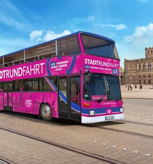 a pink double decker bus in front of a building
