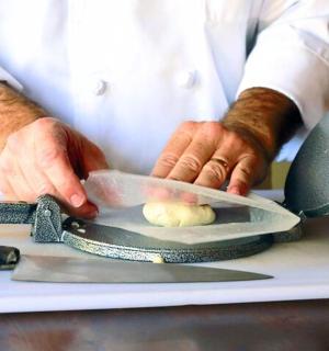 a chef cutting a onion with a knife on a cutting board