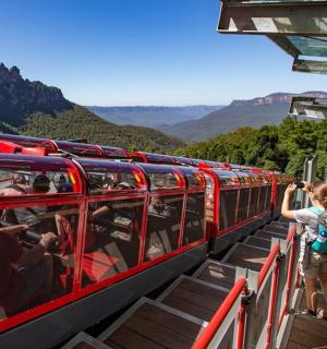 a group of people on a red train in the mountains