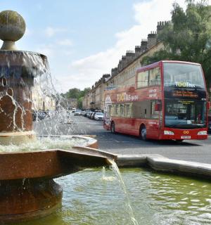 一辆红色双层巴士驶过喷泉