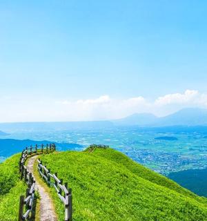 en vej på toppen af en grøn bakke med en by