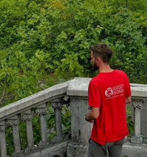a man in a red shirt standing on a railing