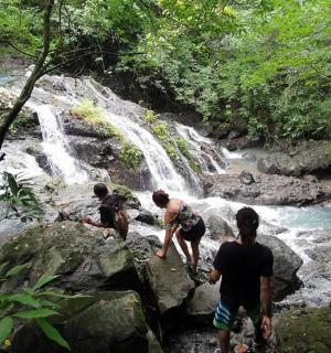 三个人站在瀑布附近的岩石上