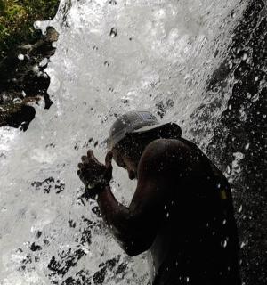 站在瀑布前水中的人