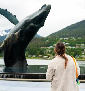 一位女士站在鲸鱼雕像旁边