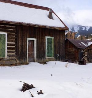stará srubová chata se sněhem na zemi