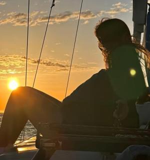 a woman sitting on a boat at sunset