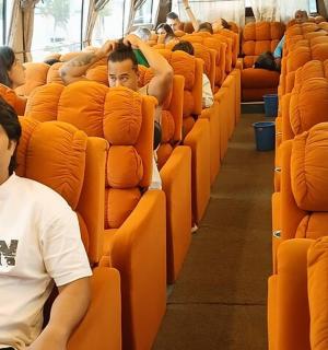 a man sitting in an orange seat on a bus