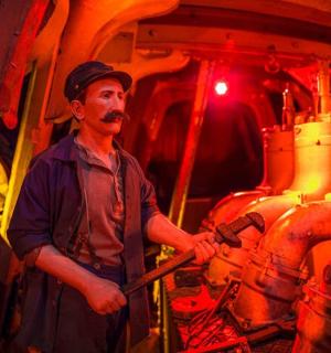 一名男子站在工厂里,手里拿着锤子