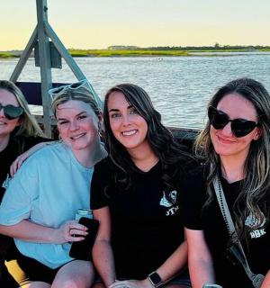 a group of women sitting on the back of a boat