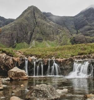 一名男子站在瀑布旁的山上