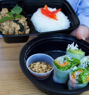 a lunch box with sushi and rice on a table
