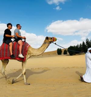 一群人骑着骆驼在沙漠中