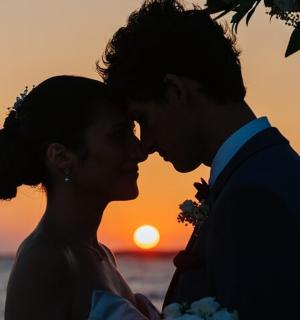 nevěsta a ženich líbající se před západem slunce