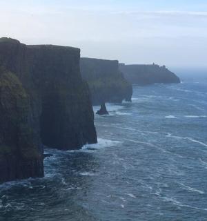a view of the ocean with cliffs in the distance