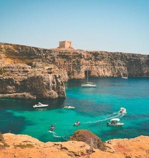 a group of boats in the water near a cliff