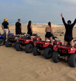 一群人站在沙地上的四轮车上