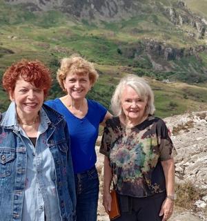 two women and a man standing on a mountain