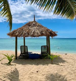 沙滩上的两把椅子和一把草伞