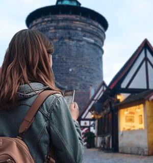 a woman holding a cell phone in front of a lighthouse