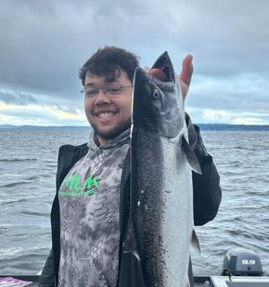 ein Mann, der auf einem Boot einen Fisch in der Hand hält