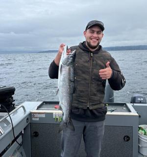 ein Mann, der auf einem Boot steht und einen Fisch hält