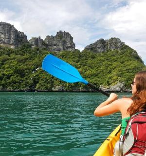一名女子在水中划着皮划艇，手里拿着桨