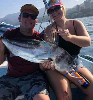 seorang lelaki dan wanita duduk di atas bot memegang ikan