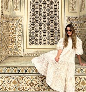 一位身穿白色连衣裙的女子坐在墙上