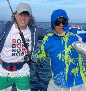 dva muži držící rybu na lodi