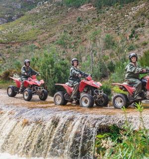 a group of people riding atvs crosses a waterfall
