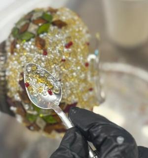 a person in black gloves holding a spoon with food on it