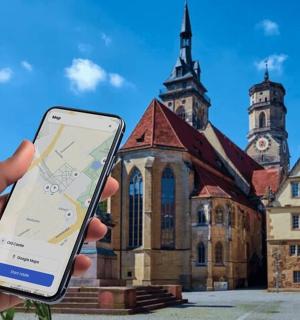 eine Person, die ein Mobiltelefon vor einem Gebäude hält