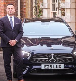 一名西装革履的男子站在一辆汽车前