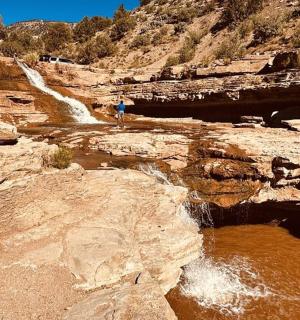 a person standing on top of a rocky mountain with a waterfall