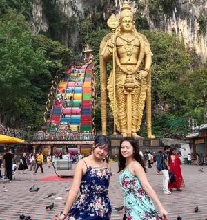 dvě ženy stojící před sochou ve městě