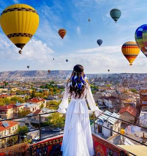 a woman standing on a balcony looking at hot air balloons