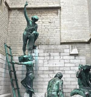 a statue of three people on the side of a building