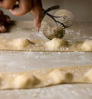 osoba používající pilu k řezání kusu těsta